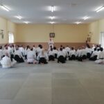 Sensei O'Connell standing talking, whilst kneeling students attend to him