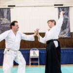 The partner's forward momentum is compromised by a small turn of their wrist