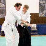 Demonstrating how to release the partners grip in a way that temporarily immobilises them.