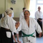 Mid-movement, the student turns her partner's wrist back on him to effect the throw.