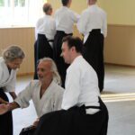 Two partners dropping downwards as the student in the middle refines their movement