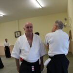 Sensei John Quinn smiling whilst his partner looks thoughtful.