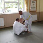 One student testing by pushing at the shoulders of another student who has just rolled backwards and forwards.